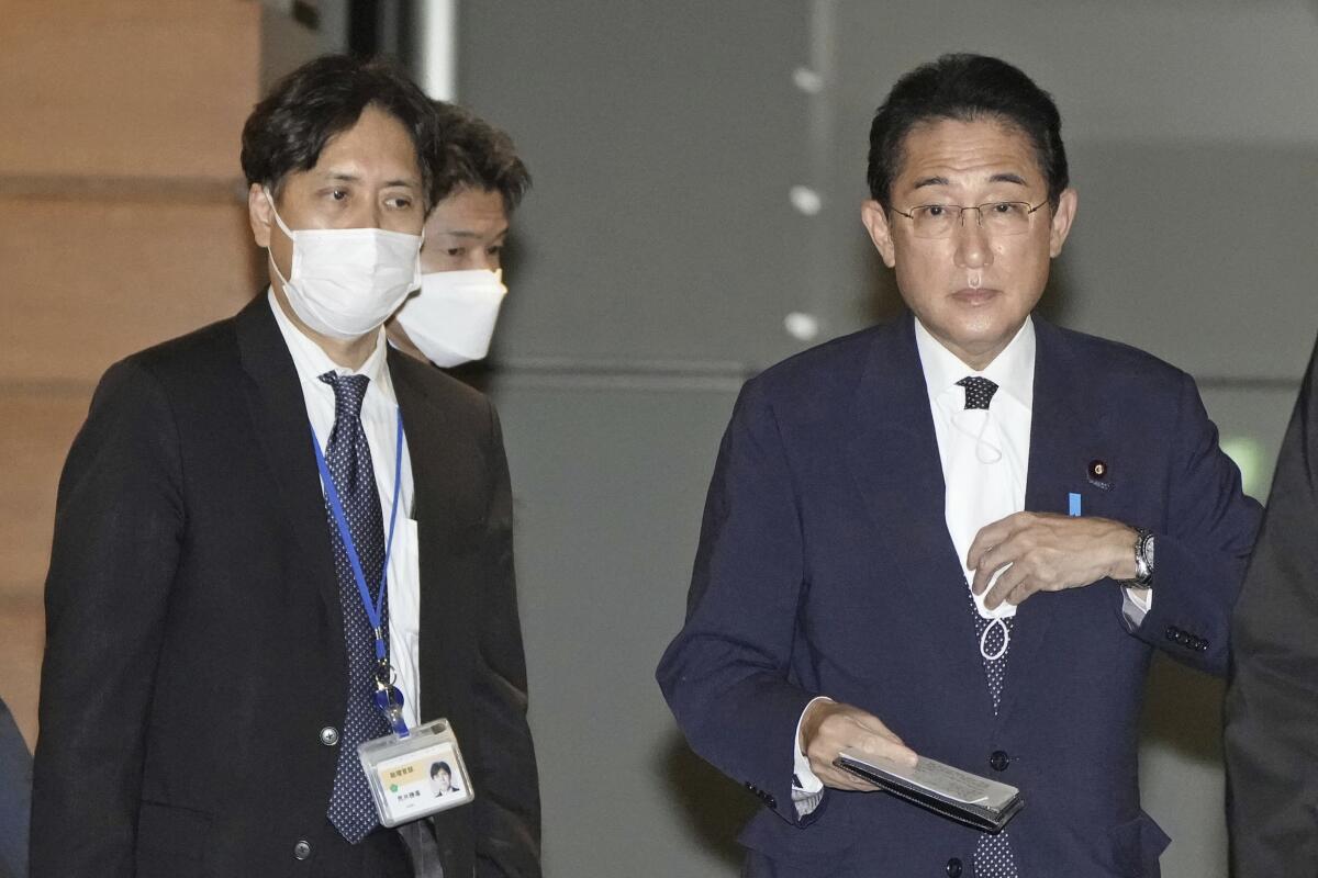 Senior aide to the prime minister Masayoshi Arai, left, walks next to Prime Minister Fumio Kishida at the Prime Minister's official residence in Tokyo, Dec. 12, 2022. Kishida told reporters Saturday, Feb. 4, 2023, that Arai was being dismissed after making discriminatory remarks about LGBTQ people. (Kyodo News via AP)