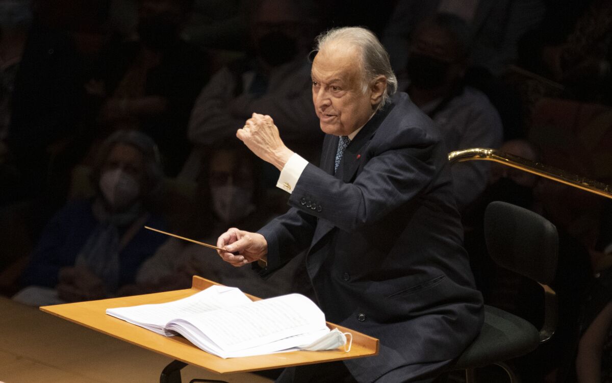 A conductor gestures while leading an orchestra 