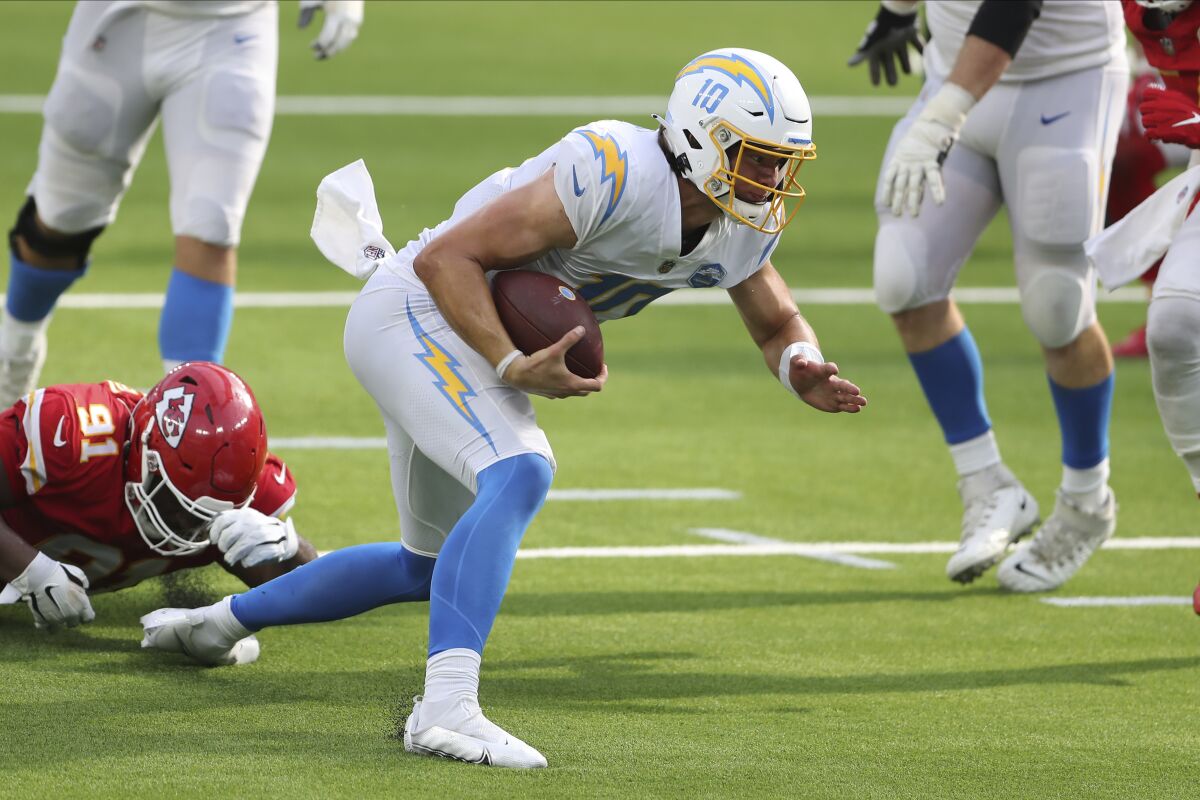 Chargers quarterback Justin Herbert (10) tries to get down on the turf before getting hit by a Kansas City Chiefs defender.