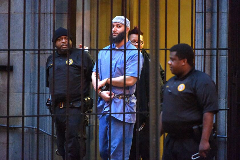 Officials escort "Serial" podcast subject Adnan Syed from the courthouse at the end of the first day of hearings for a retrial.