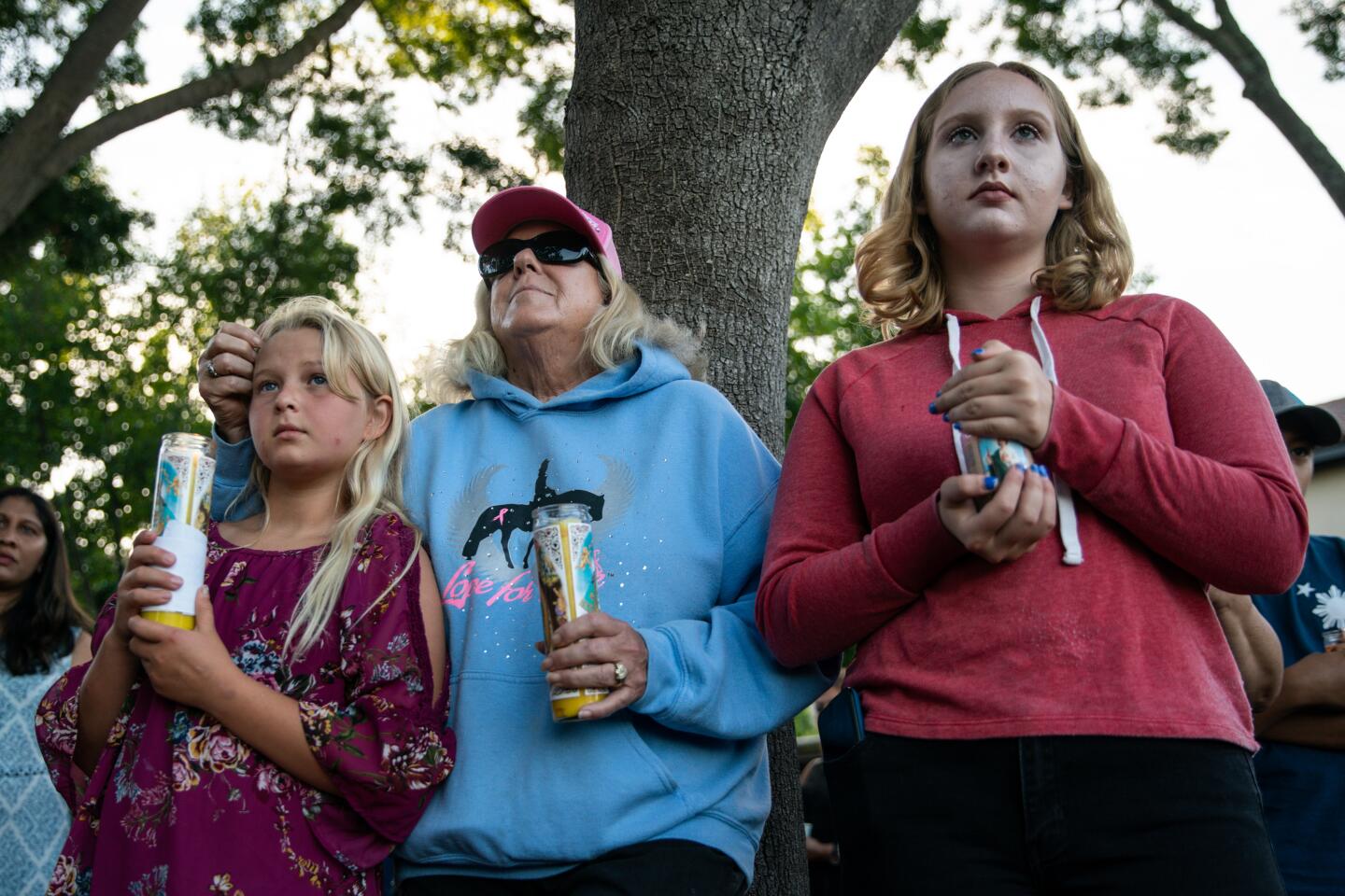 Madison Ferchette, 10, her grandmother, Laurie Ferchette, 69, and Julissa Frechette, 16, listen to speakers during a candlelight vigil at Gilroy City Hall on Monday.