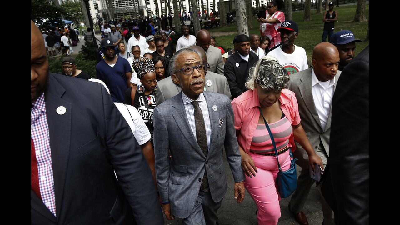 The Rev. Al Sharpton, center, and Gwen Carr, mother of Eric Garner, leave a July 18 rally in Brooklyn commemorating the one-year anniversary of Garner's death.