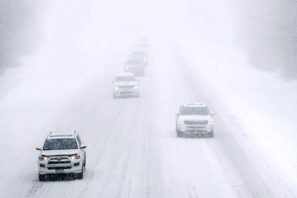 Cars drive on a snow-covered interstate in nearly whiteout conditions during a winter storm