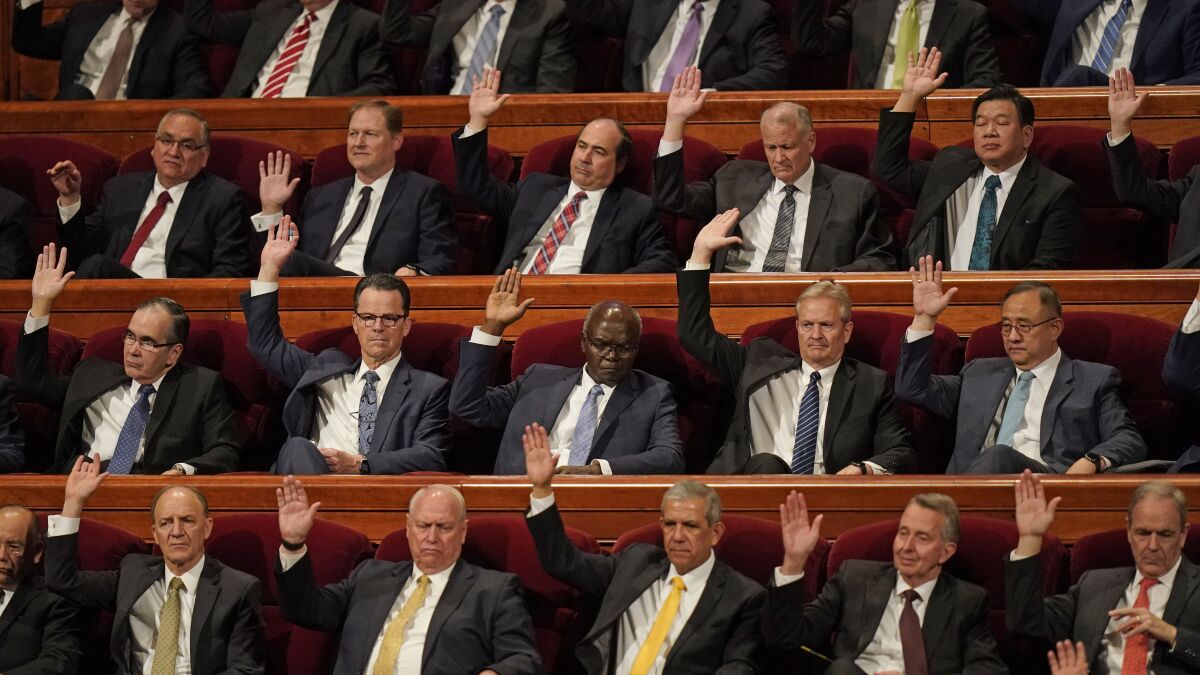 Church leaders raise their hands during a sustaining vote during The Church of Jesus Christ of Latter-day Saints' twice-yearly conference Saturday, April 2, 2022, in Salt Lake City. Top leaders of the Church of Jesus Christ of Latter-day Saints addressed a wide range of topics at their conference, including LGBTQ non-discrimination laws, war in Ukraine and political polarization. (AP Photo/Rick Bowmer)