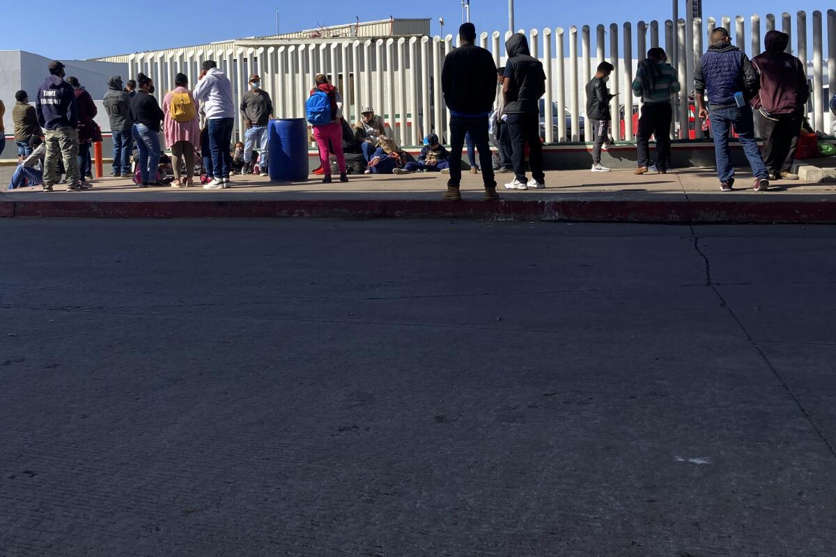 Migrantes en espera de noticias en un cruce fronterizo en Tijuana, México.