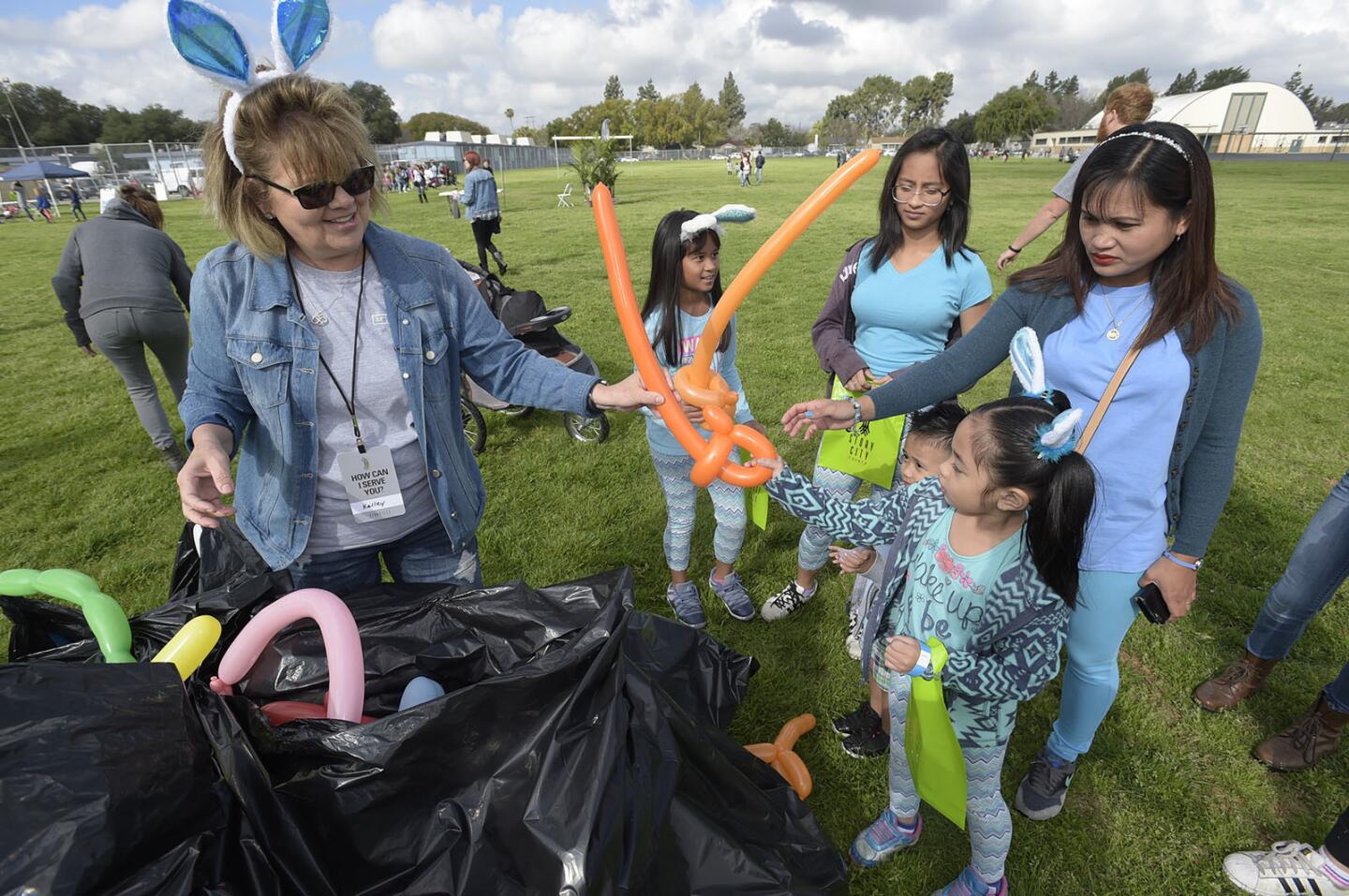 Volunteer Kelly Mize, left, hands out balloons to some of the hundreds of attendees at the 2018 Greater L.A. Easter Egg Drop hosted by Story City Church at Luther Burbank Middle School in Burbank on Saturday, March 24, 2018.