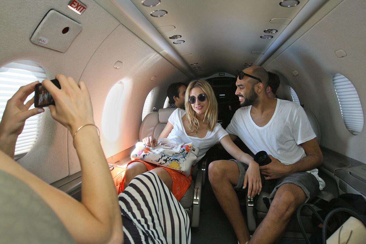 BURBANK, CALIFORNIA - APRIL 11, 2014: Izzy Lawrence (far left) photographs Sophie Ball (middle) and Tom Hardy (right) aboard Surf Air's Pilatus PC-12 on April 11 in Burbank. All from the United Kingdom, they were heading from Bob Hope Airport in Burbank to the Coachella Valley Music & Arts Festival. Surf Air is a new startup that acts like an Uber for private jets around California. As Coachella has become increasingly resort-ified and stratified for those who can pay, the firm wants to take the last egalitarian, unwristbanded part of Coachella - driving down the 10 to Indio - out of the equation, with nonstop private flights from Burbank to an airport nearly directly outside the festival walls. If music festivals used to be about communing with the sweaty masses, Surf Air is the latest turn in a festival culture where big spenders can avoid the plebes entirely - even on the way there. Surf Air has 18 daily flights between Burbank, Hawthorne, Santa Barbara, San Carlos and as of May 1 they will be flying to the Lake Tahoe region. (Gary Friedman/Los Angeles Times)