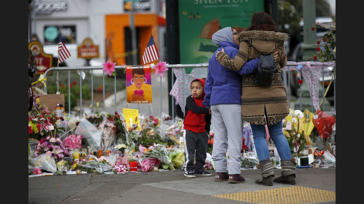 Jacob Ramirez, 4, left, looks on while his grandmother Eva Ramirez, 52, consoles Hillary Morse, 22, right, of Oakland near the site of the warehouse fire in Oakland.