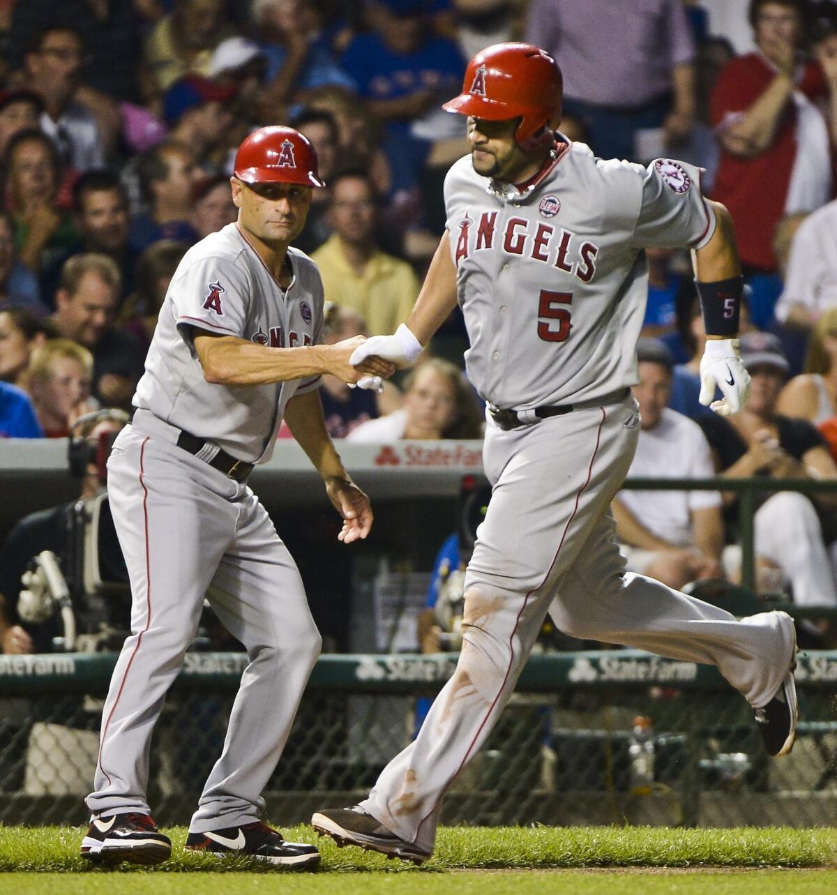 Angels slugger Albert Pujols is congratulated by third base coach Dino Ebel after hitting a home run against the Chicago Cubs on July 9.