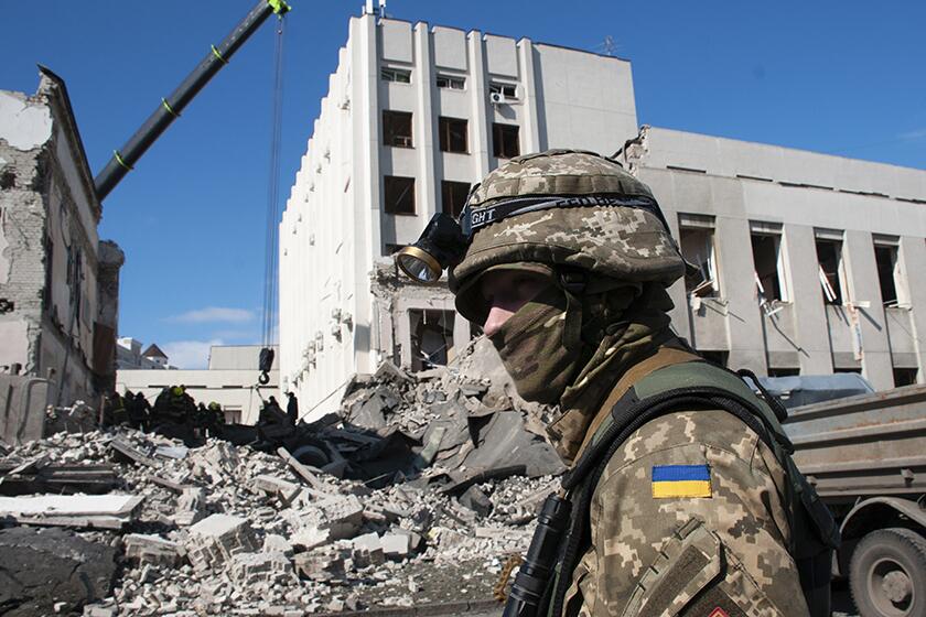 A Ukrainian serviceman guards near a building that was damaged by shelling in Kharkiv, Ukraine, on Friday.