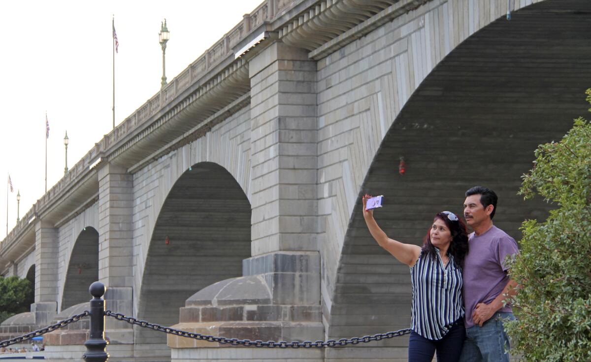 Claudia and Rafael Lopez take a selfie in front of the London Bridge in Lake Havasu City, Ariz., on Saturday, Sept. 25, 2021. Lake Havasu City is playing up its roots with a month of celebratory events marking the 50th anniversary of the dedication of the London Bridge after its piece-by-piece rebuild in the resort town along the Colorado River. (Daisy Nelson/Today's News-Herald/HavasuNews.com via The AP)