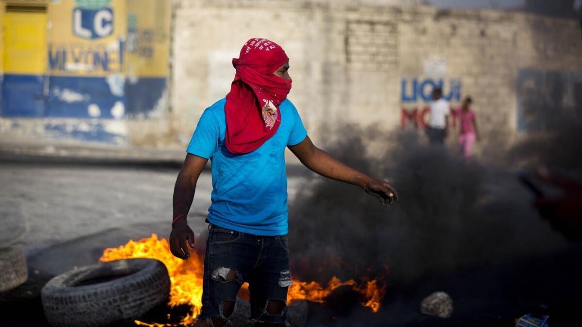 A masked protester sets up a barricade in the middle of the street July 7 in Port-au-Prince, Haiti. Thousands took to the streets after the government announced a sharp increase in gasoline prices.