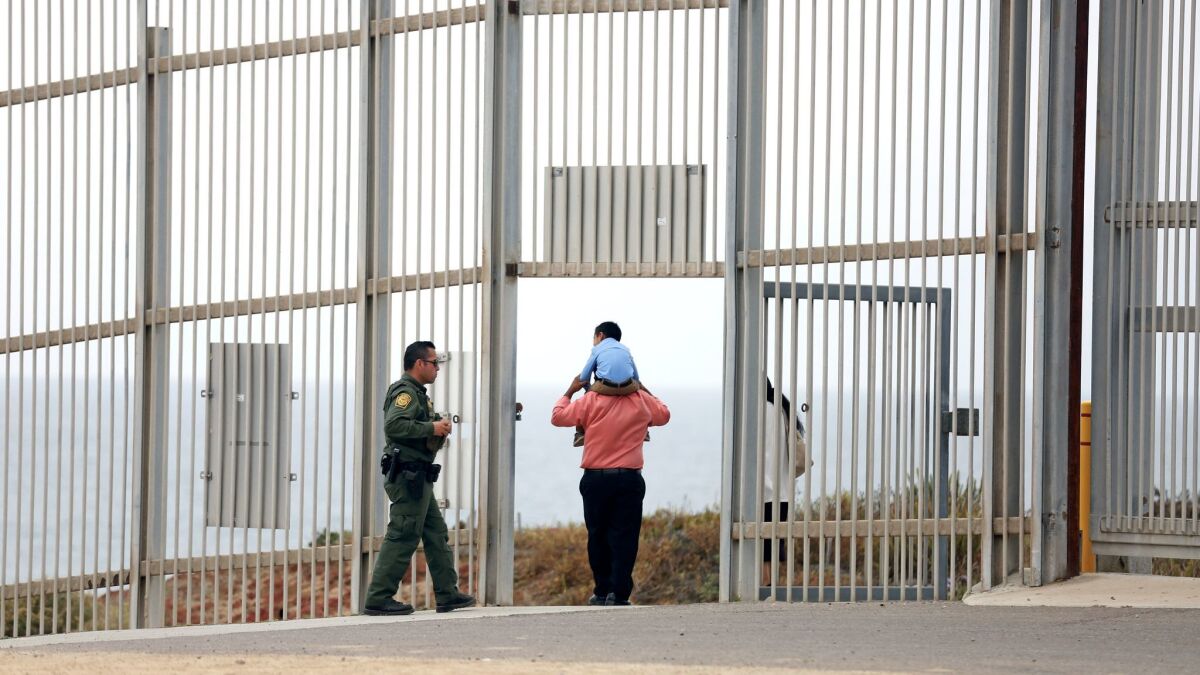 A U.S. Border Patrol agent escorts a family through the secondary fence back to Border Field State Park, San Diego, after visiting people in Friendship Park, Tijuana.