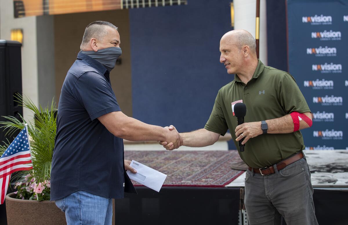 Chris Brahney, right, with the Nuvision Credit Union, gives a check to Mike Pradin, a Los Angeles County Firefighter.