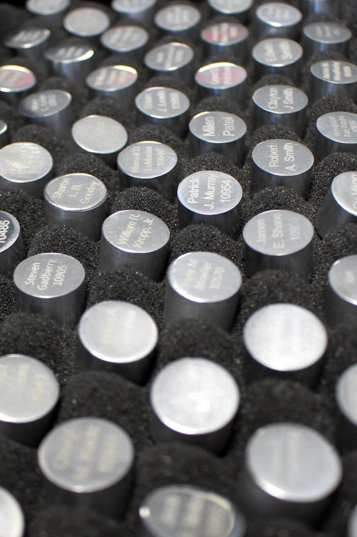 The tops of silver metal capsules arranged in a container.