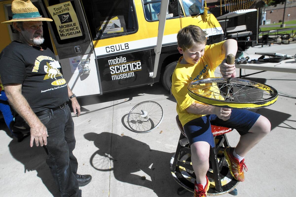 Christopher Burke experiments with a rotating platform that he could control by tilting a bicycle wheel during the 2015 "Astounding Inventions" competition at Irvine Valley College. This year's contest is Saturday.