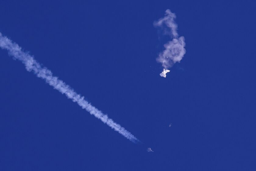  The remnants of a large balloon drift above the Atlantic Ocean with a fighter jet  seen below it on Feb. 4
