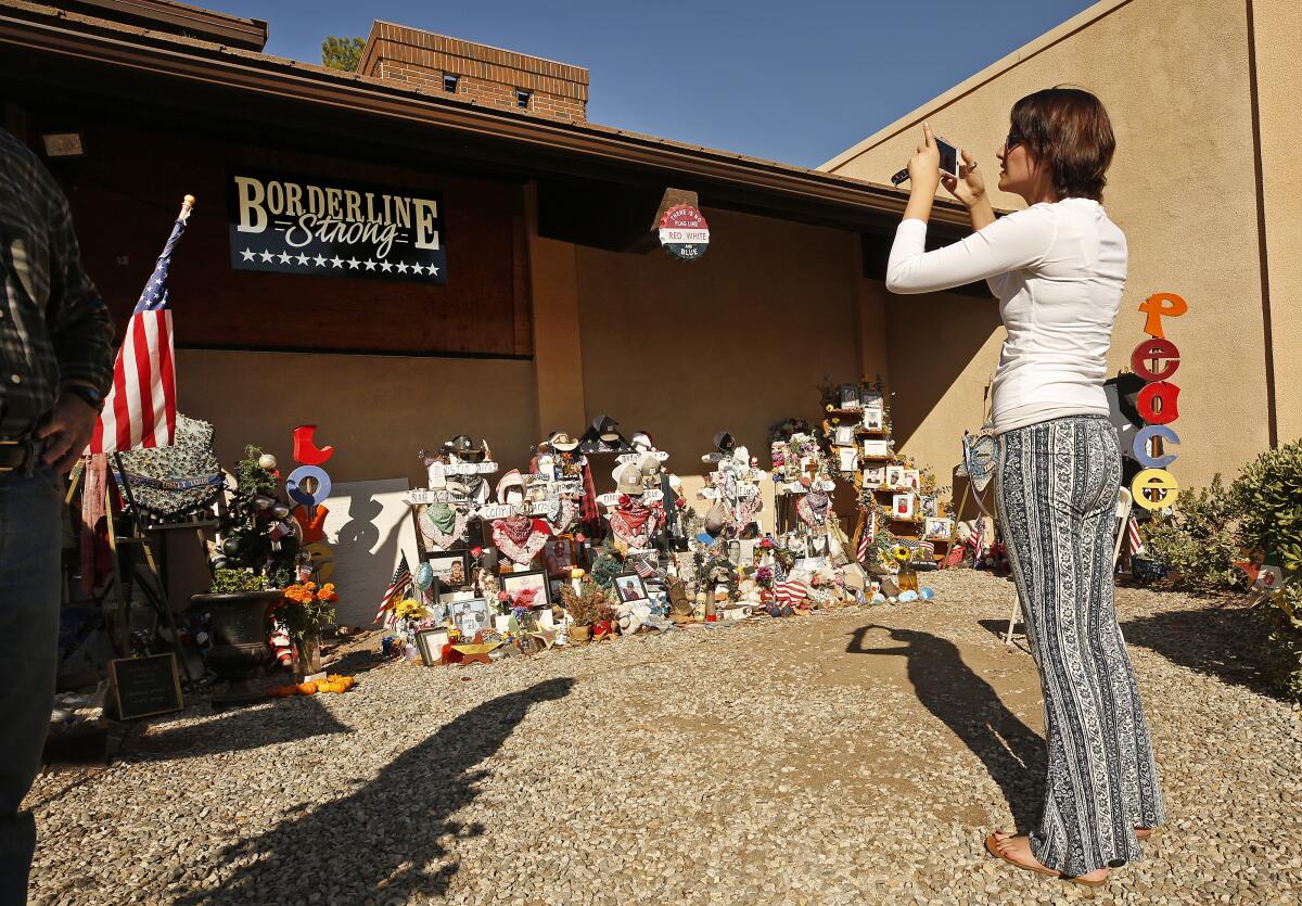 A woman in front of Borderline Bar and Grill with the sign "Borderline Strong"