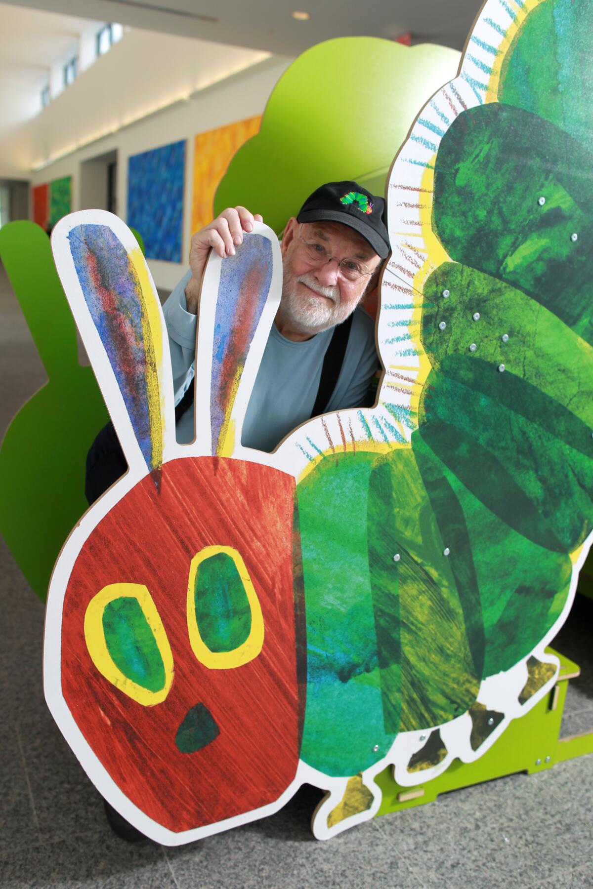 Eric Carle stands with large cutout of the iconic image from his children's book, "The Very Hungry Caterpillar"