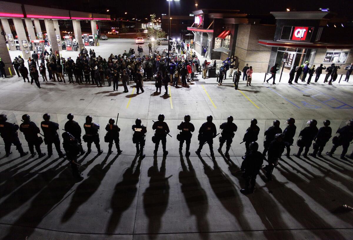 Police officers in riot gear hold a line in October 2014 as they watch demonstrators in St. Louis protest the shooting deaths of Michael Brown and VonDerrit Myers Jr.