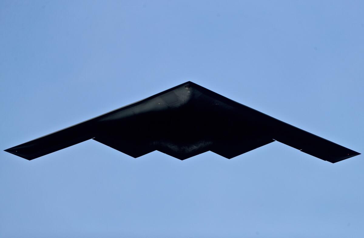A black V-shaped aircraft against a bright blue sky