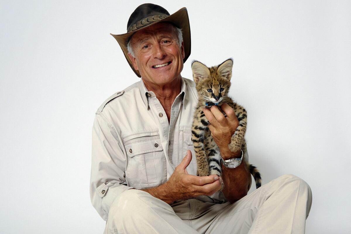 Wildlife advocate Jack Hanna sits in khakis and holds a serval cub.