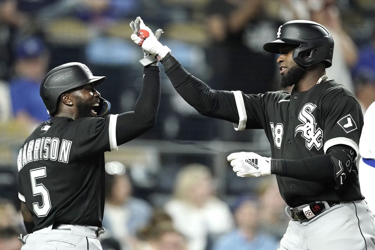 Chicago White Sox's Luis Robert, right, celebrates with Josh Harrison (5) after hitting a two-run home run during the tenth inning of a baseball game against the Kansas City Royals Monday, May 16, 2022, in Kansas City, Mo. (AP Photo/Charlie Riedel)