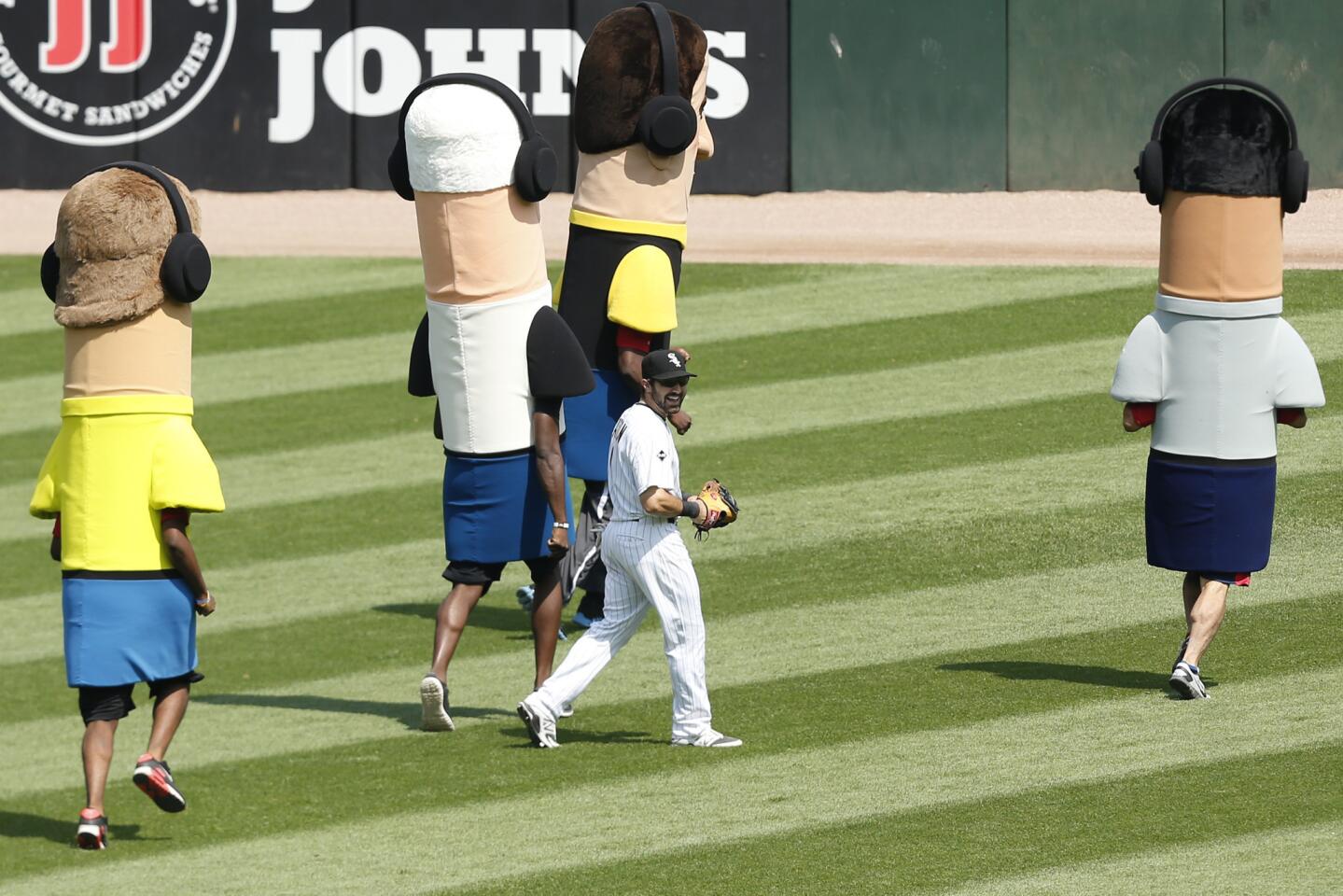 White Sox center fielder Adam Eaton runs to his position as a seventh inning as broadcaster mascots give chase.