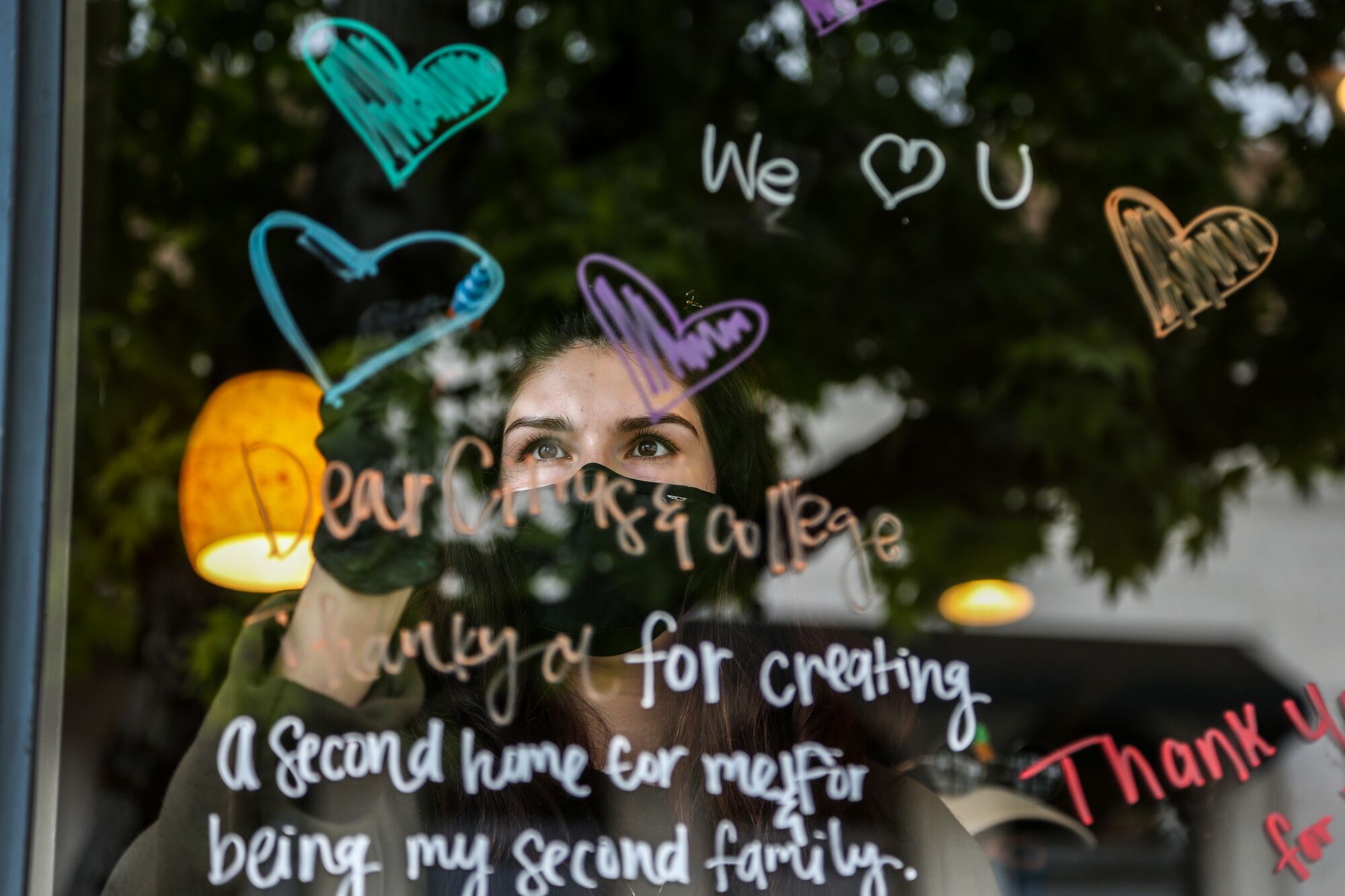 A Starbucks employee in Covina writes inspiring messages on the store window during the COVID-19 pandemic.