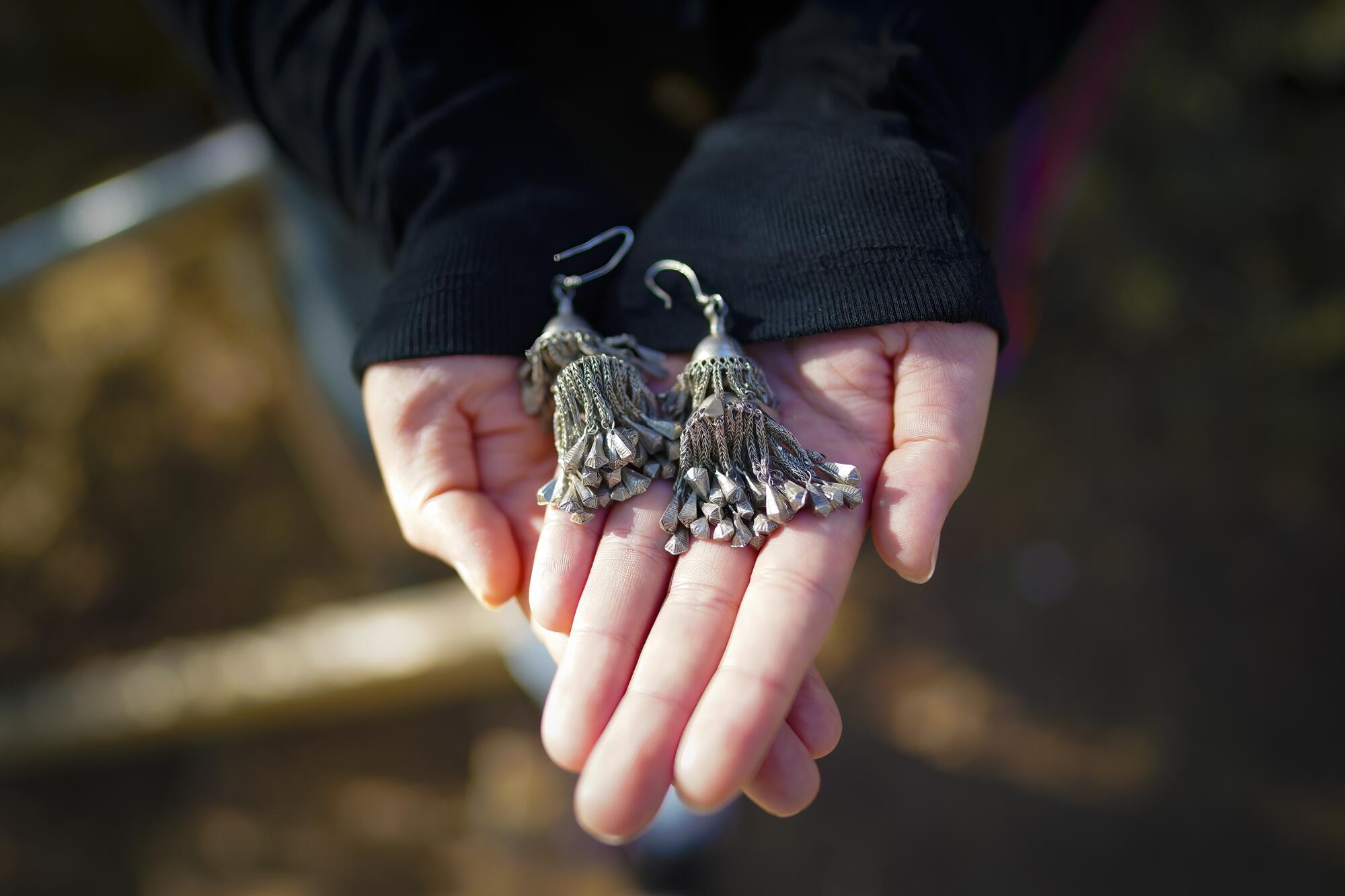 Hands hold ornate silver earrings 