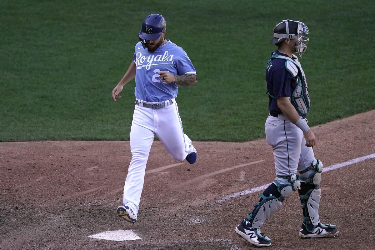Kansas City Royals' Kyle Isbel crosses the plate behind Seattle Mariners catcher Cal Raleigh to score on a single by Hunter Dozier during the sixth inning of a baseball game against the Seattle Mariners Sunday, Sept. 25, 2022, in Kansas City, Mo. The Royals won 13-12. (AP Photo/Charlie Riedel)