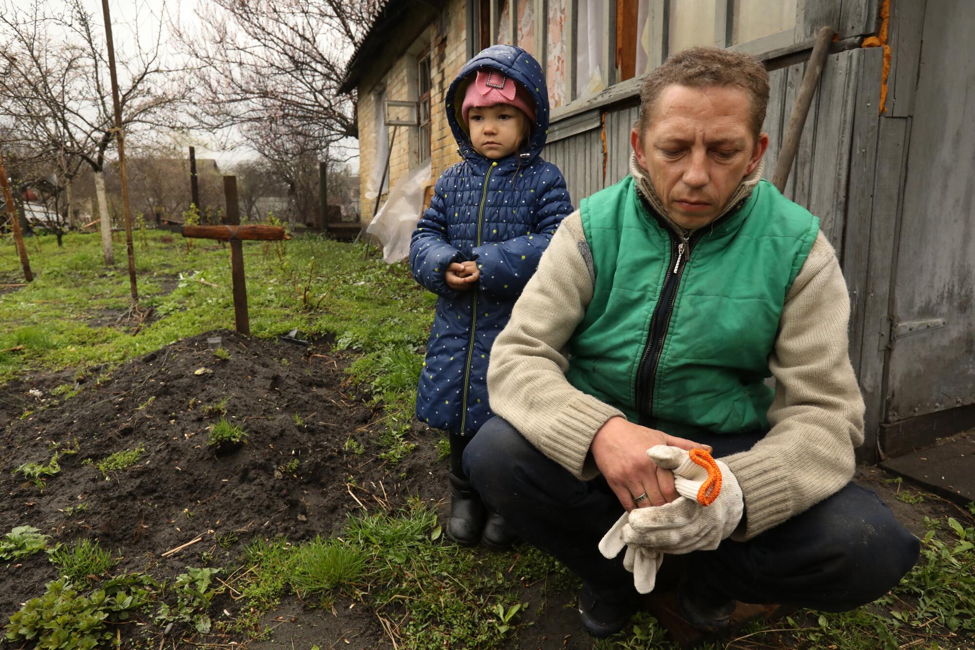 Anatolii Oliinyk, age 38, right, buried his father in the garden three days ago when he returned home to Bucha 