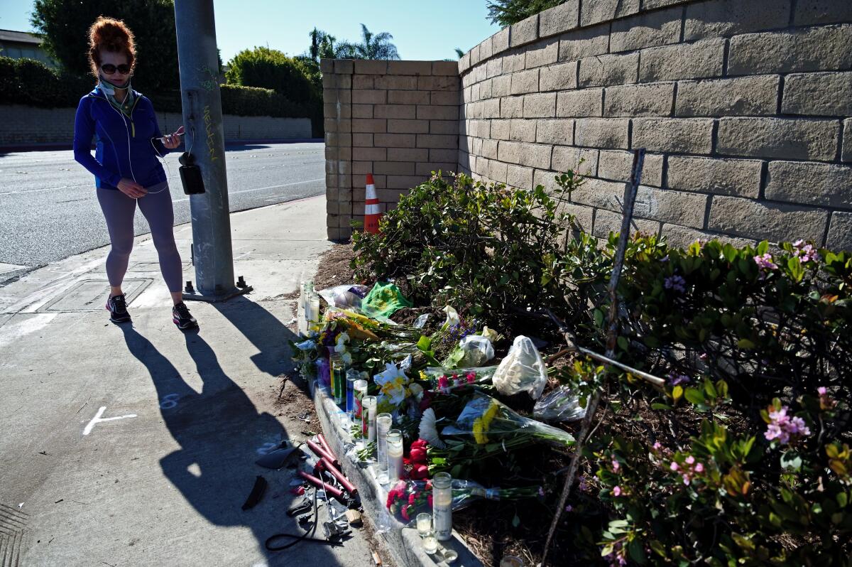A woman passes by a growing memorial for two teenage brothers in Huntington Beach