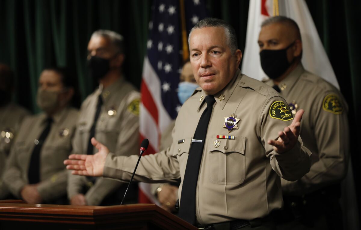 L.A. County Sheriff Alex Villanueva at a lectern with arms outstretched