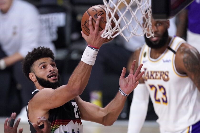 Denver Nuggets guard Jamal Murray, left, goes up for a shot attempt as Los Angeles Lakers' LeBron James.