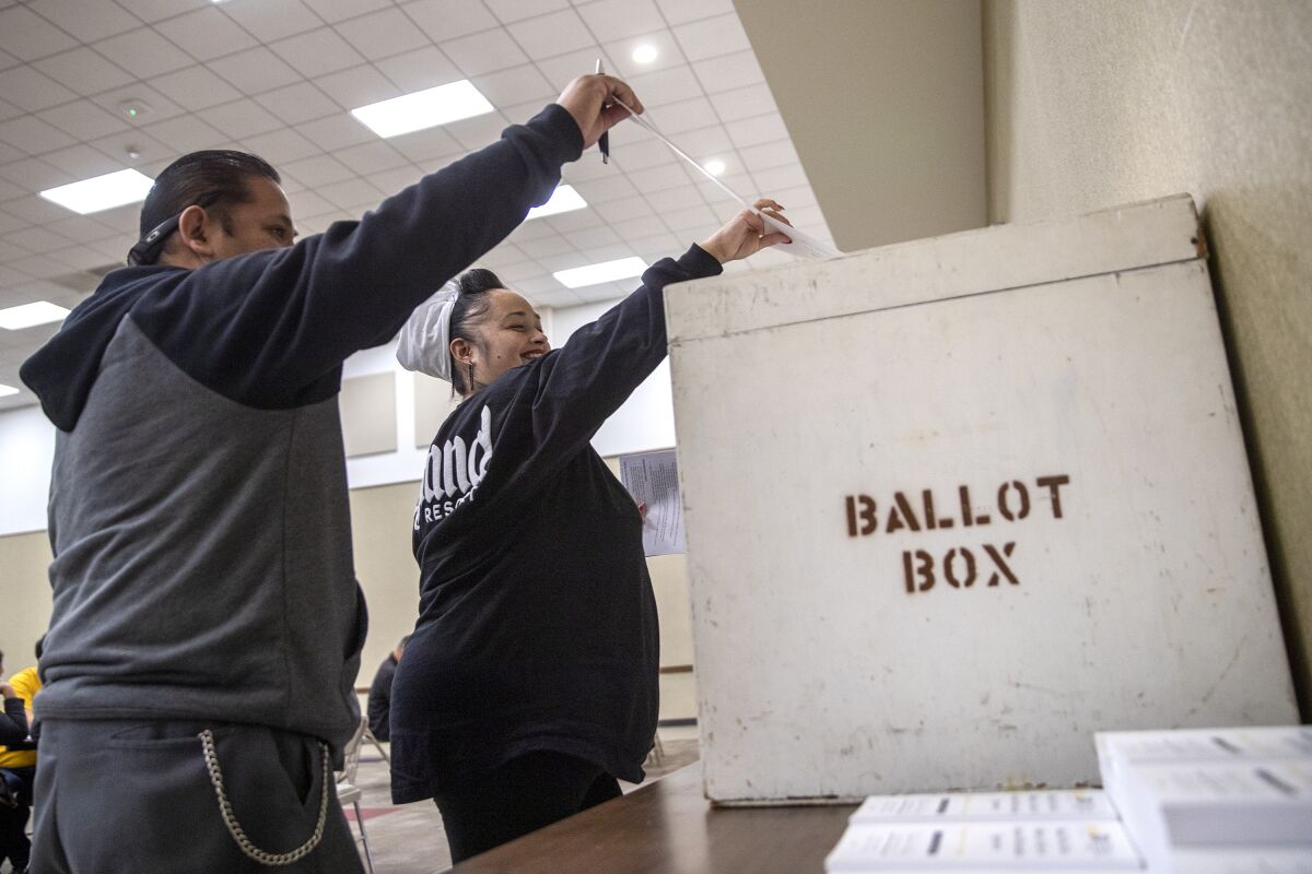 Albertsons employees Marissa Pena and Stephen Sanchez deliver their votes to a ballot box. 
