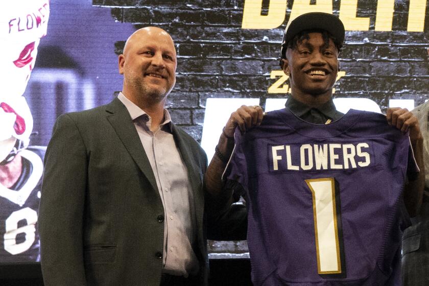 Baltimore Ravens first round draft pick Zay Flowers, second from left, holds a jersey.