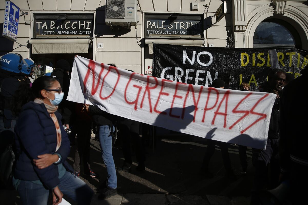 People hold a banner reading No Green Pass during a protest in Rome, Friday, Oct. 15, 2021. Protests erupted in Italy on Friday as one of the most stringent anti-coronavirus measures in Europe went into effect, requiring all workers, from magistrates to maids, to show a health pass to get into their place of employment. The so-called “Green Pass” shows proof of vaccination, a recent negative test or of having recovered from COVID-19 in the past six months. Italy has required it to access all sorts of indoor activities for weeks, including dining , visiting museums and theaters and on long-distance trains. (Cecilia Fabiano/LaPresse via AP)