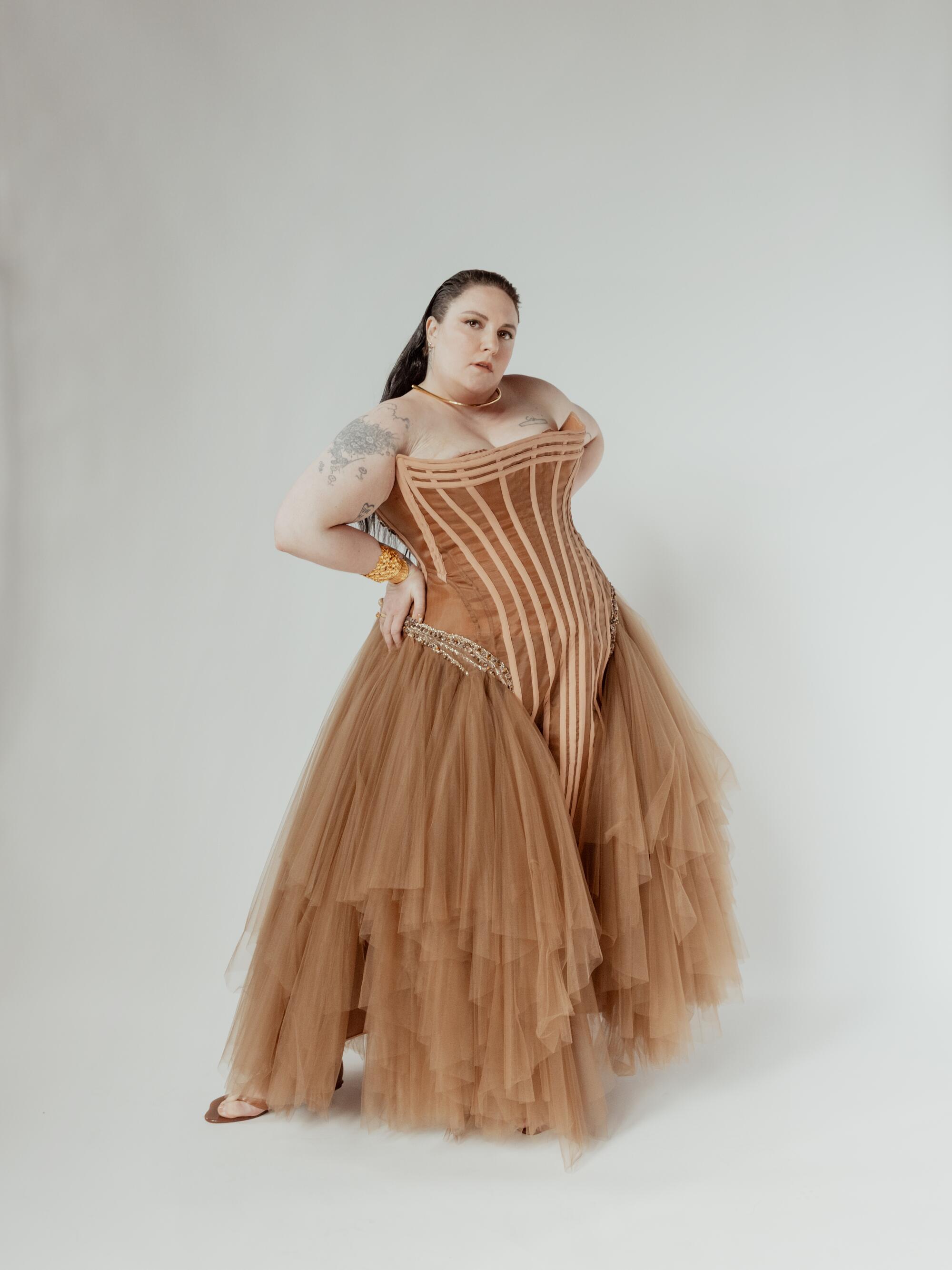 A woman in a brown corset dress poses for a portrait