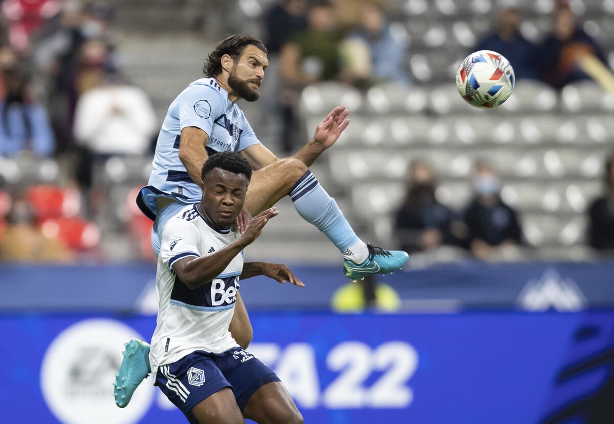 Sporting Kansas City's Graham Zusi, top, and Vancouver Whitecaps' Javain Brown , bottom, vie for the ball during the first half of MLS soccer match action in Vancouver, British Columbia, Sunday, Oct. 17, 2021. (Darryl Dyck/The Canadian Press via AP)
