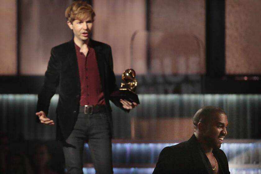 Kanye West, right, leaves Beck alone onstage to finish accepting the album of the year award at the Grammys in Los Angeles on Feb. 8.