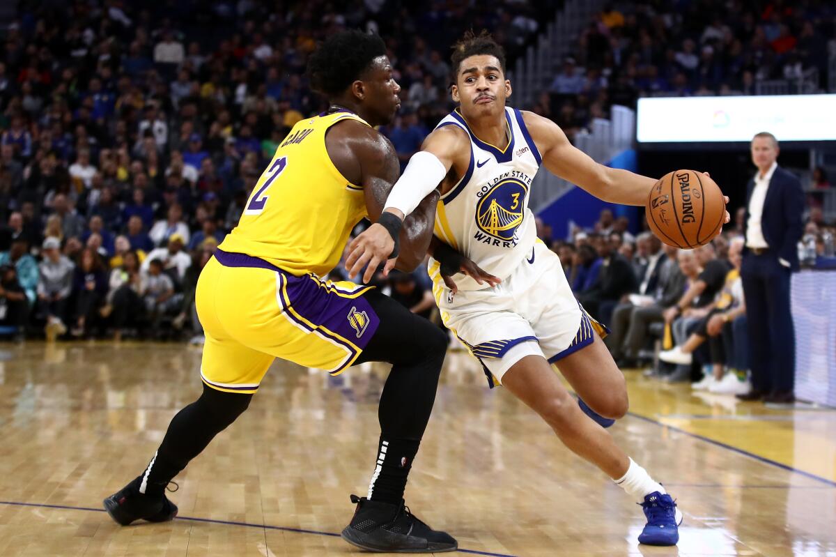 Golden State Warrior guard Jordan Poole, right, tries to drives on Lakers forward Devontae Cacok.