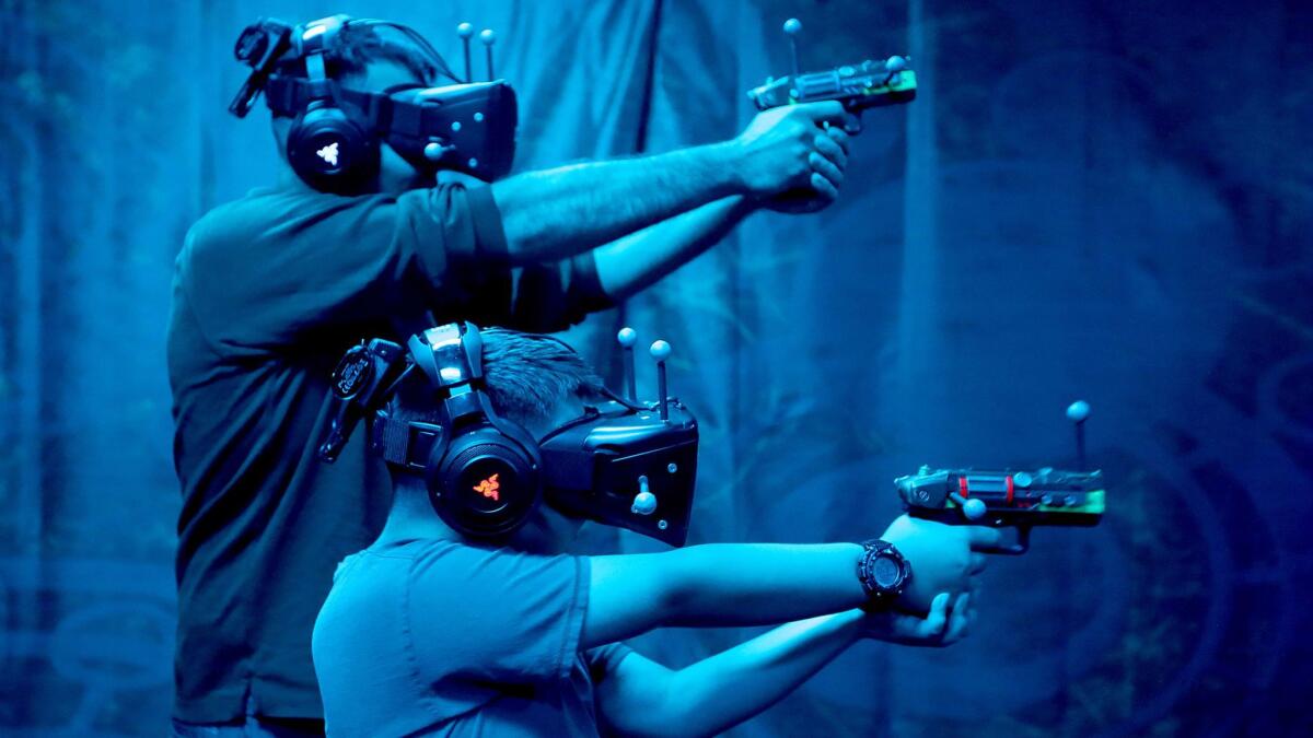 Knott's Berry Farm visitors Derek Phelps and his brother Tyrus, 8, play a round of VR Showdown in Ghost Town. Attractions that include a gaming element are increasingly popular at regional theme parks.