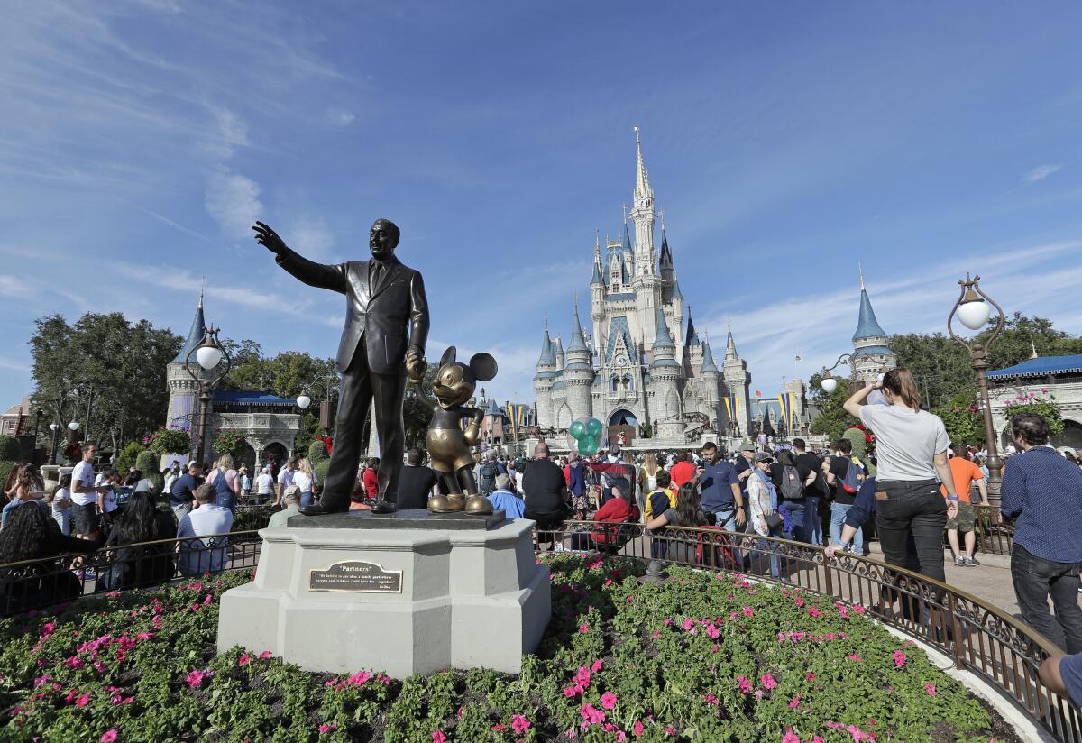 Fotografía de archivo del 9 de enero de 2019 de visitantes en el parque temático cerca de una estatua de Walt Disney y Mickey Mouse frente al castillo de Cenicienta en Magic Kingdom en Walt Disney World en Lake Buena Vista, Florida. (AP Foto/John Raoux, Archivo)