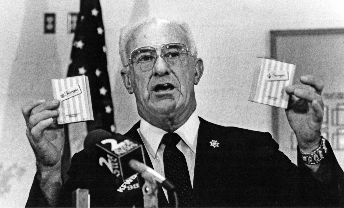 Former San Bernardino County Sheriff Floyd Tidwell holds up confiscated bottles of perfume during a 1988 news conference.