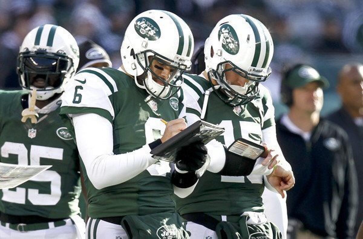 Former starting quarterback Mark Sanchez (6) and reserve Tim Tebow (15) check their playlist during the Jets' game against the Chargers on Sunday.