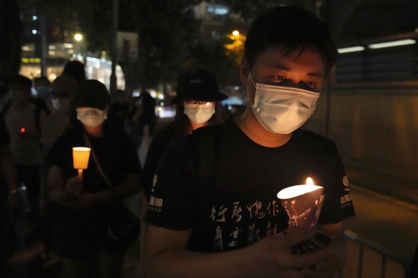 People walk with candles to mark the anniversary of the military crackdown on a pro-democracy student movement in Beijing, outside Victoria Park in Hong Kong, Friday, June 4, 2021. A member of the committee that organizes Hong Kong's annual candlelight vigil for the victims of the Tiananmen Square crackdown was arrested early Friday on the 32nd anniversary. (AP Photo/Kin Cheung)