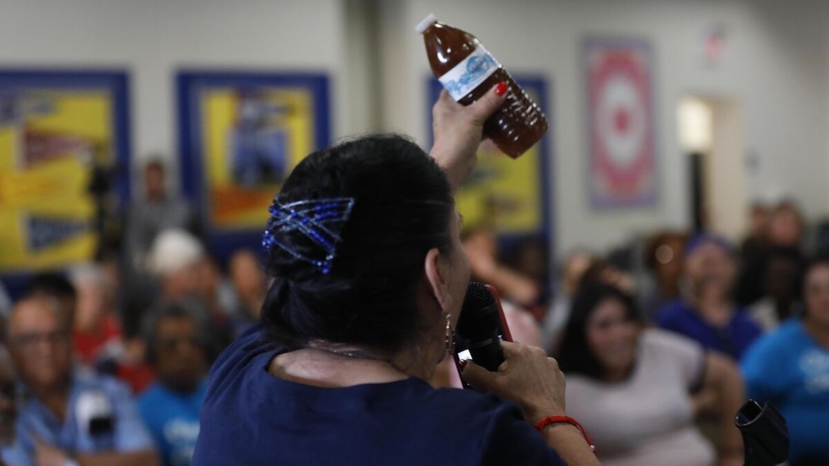 Compton resident Maria Villarreal holds up a bottle containing brown water that she said came from the tap in her home.