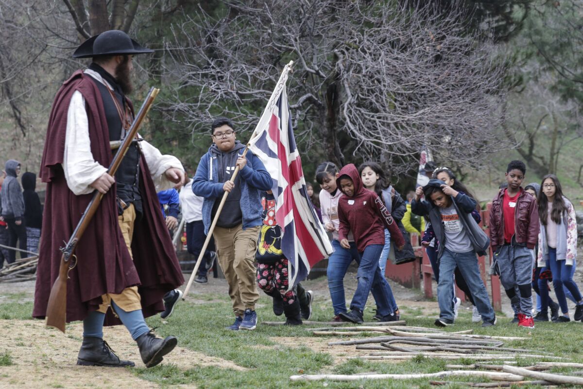 Michael Dougher, enacting the character of a rifleman teaching the colonists to fight for their liberties, leads a group of schoolchildren visiting Riley's Farm.