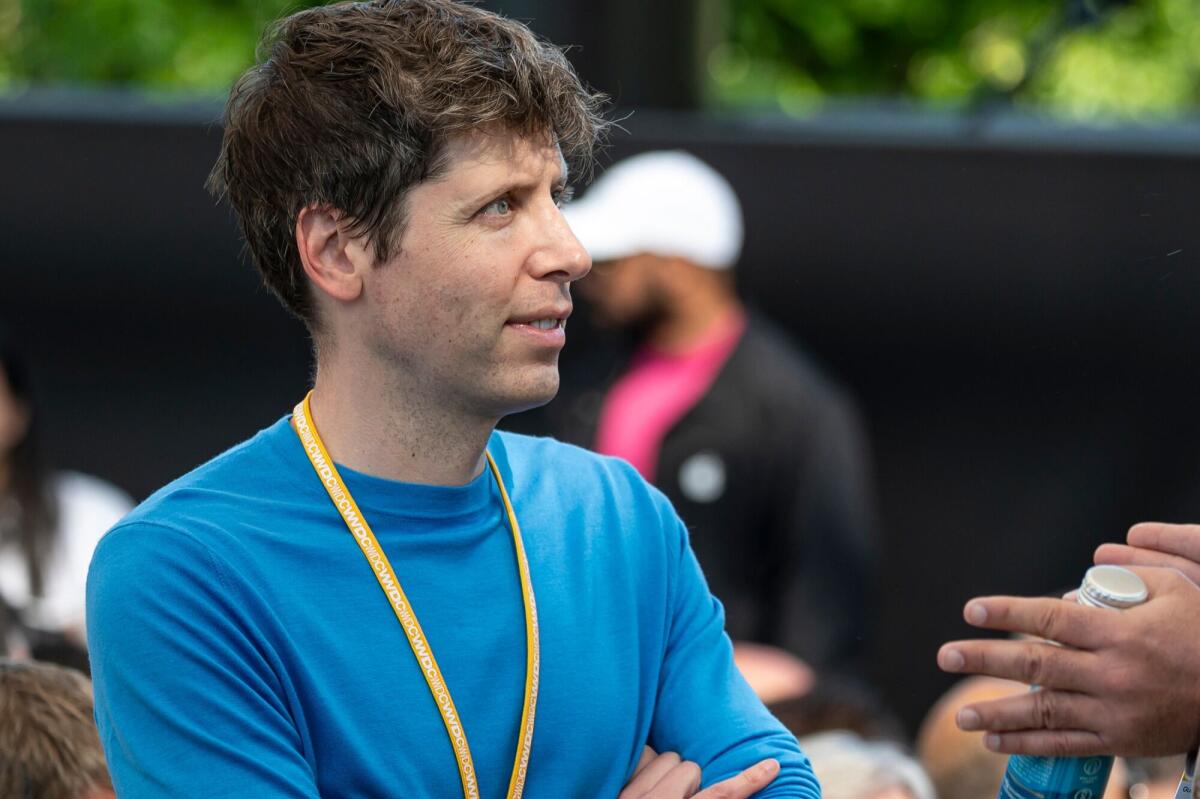 Sam Altman in a blue shirt looks to the right